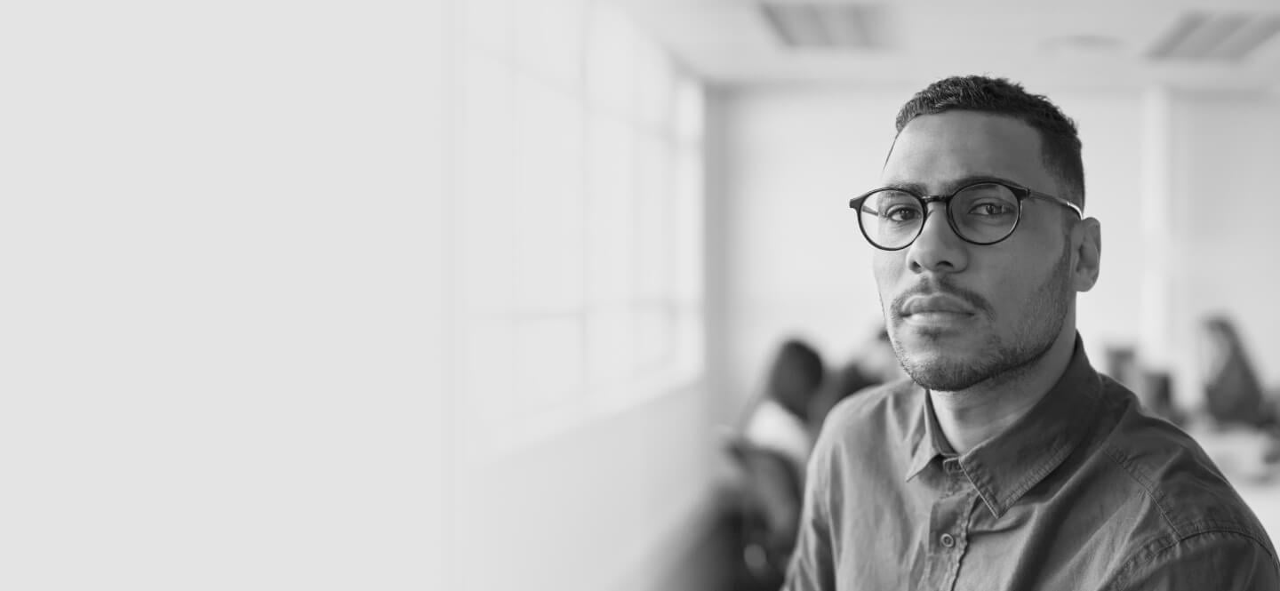 Man wearing dress shirt and glasses in an office looking into camera