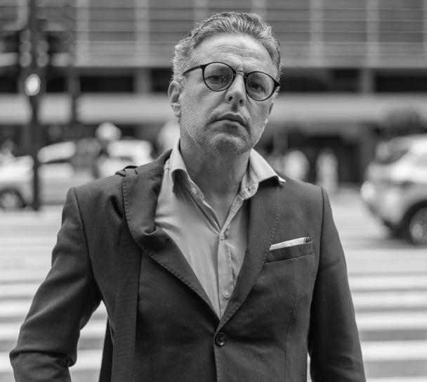 Suit-wearing man with glasses on the street looking into camera