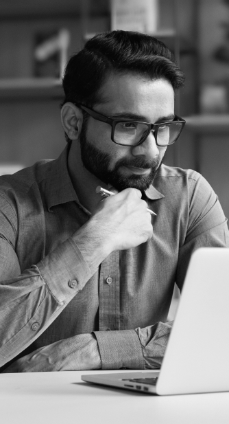 Man wearing glasses looking at laptop in office