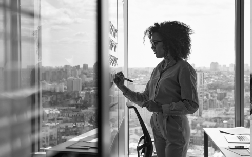 Woman writing on whiteboard in office