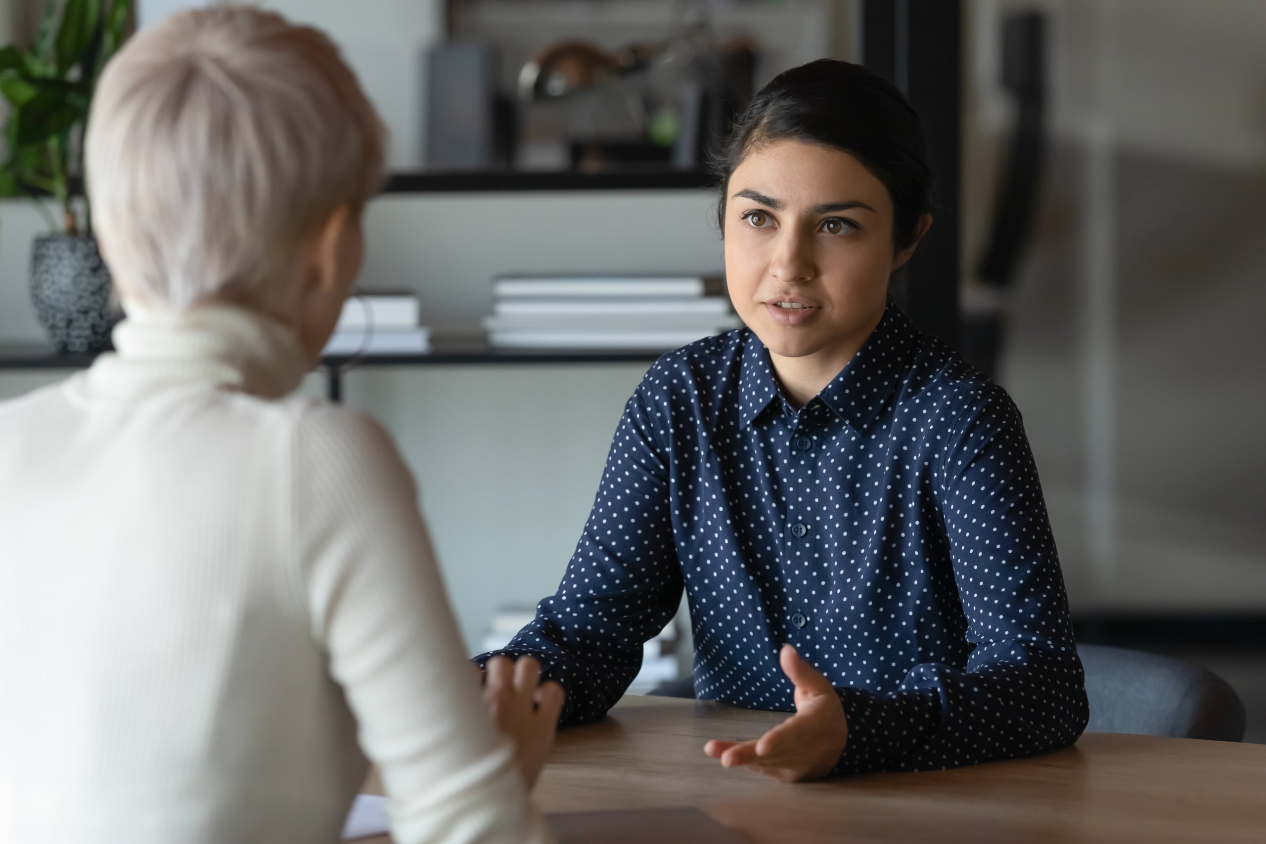 Two women in work clothes talking to each other