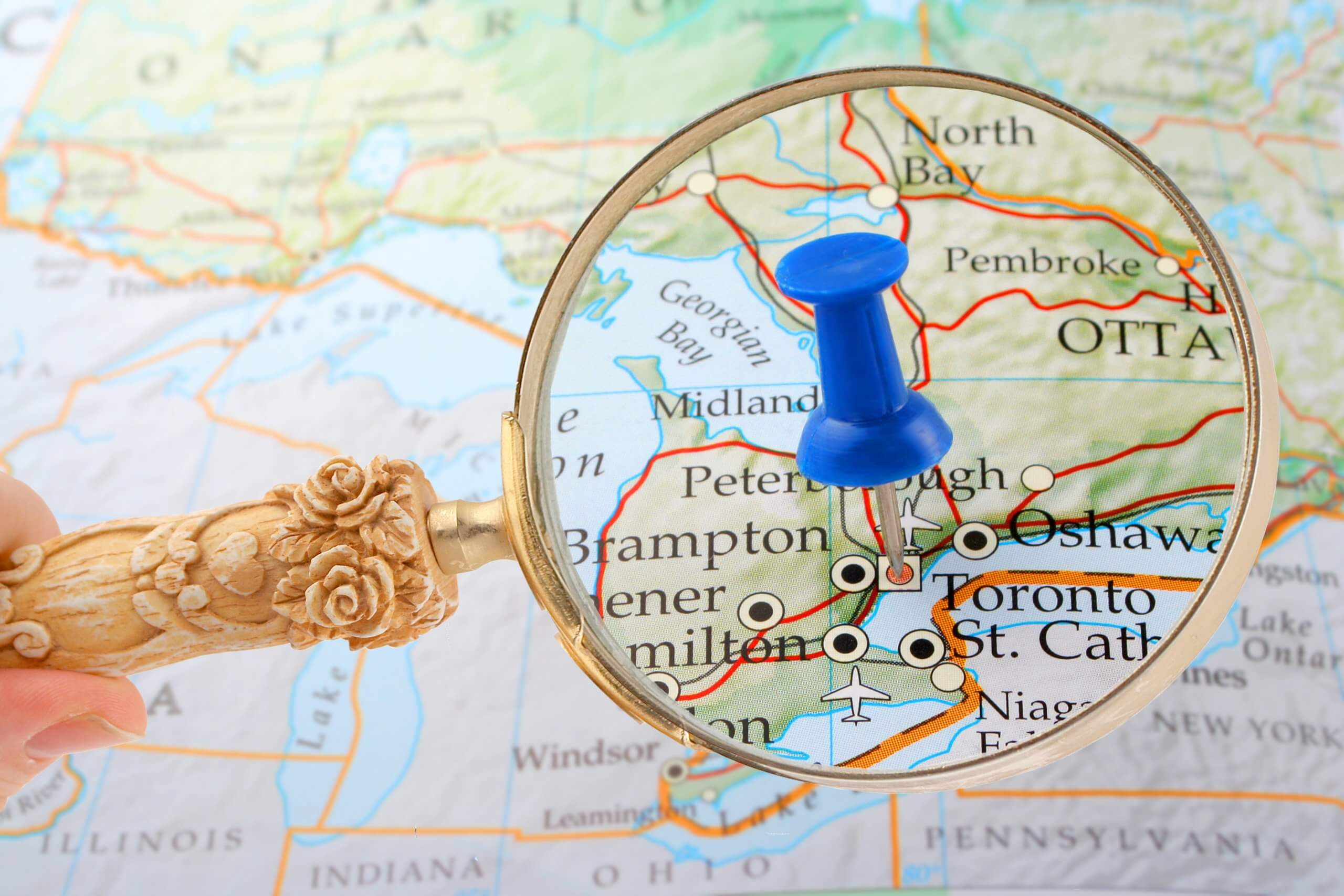 Magnifying glass showing push pin pointing to southern Ontario on a map