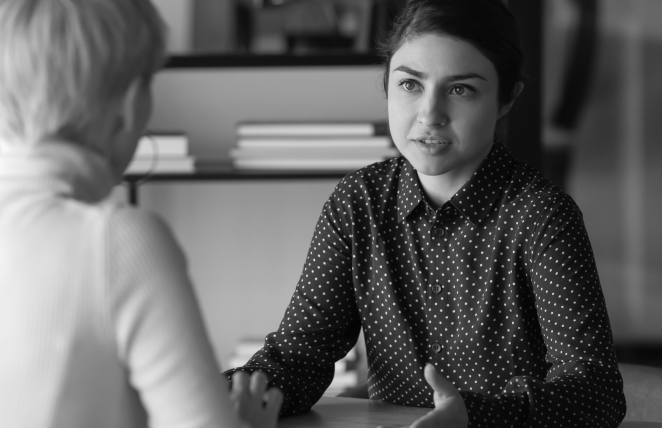 Two women in work clothes talking to each other