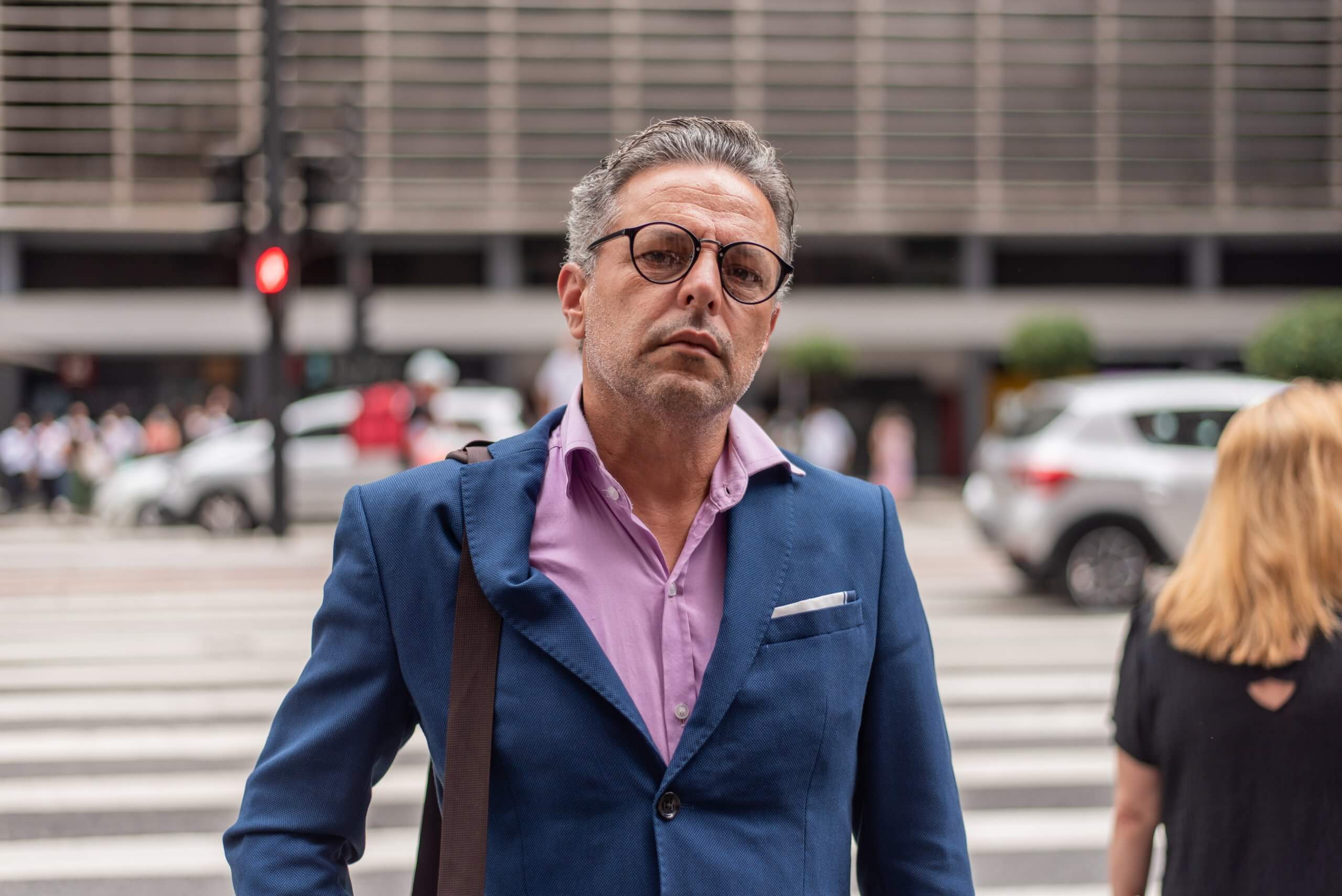 Suit-wearing man with glasses on the street looking into camera